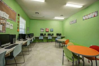 a classroom with green walls and orange and blue chairs